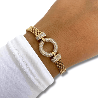 Gold bracelet with circular design worn on a wrist against a white background