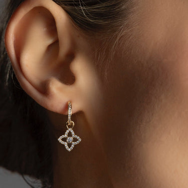Close-up of a person wearing a diamond earring with a neutral background
