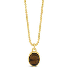 A gold chain necklace with an oval pendant featuring a brown tiger's eye stone in a gold bezel, shown against a plain white background.