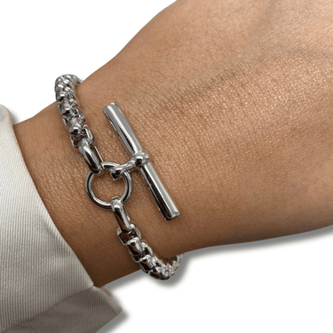 Silver chain bracelet with a clasp on a wrist against a neutral background