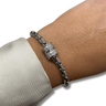 Silver bracelet with a decorative clasp on a wrist against a neutral background