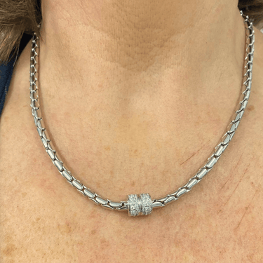 Silver chain necklace with a decorative clasp on a person's neck