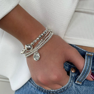 Person wearing multiple bracelets on a wrist with a blurred background
