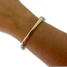A polished gold-plated metal bangle bracelet with silver-plated end caps, shown worn on a person's wrist against a white background.