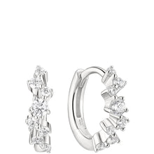 A pair of silver huggie hoop earrings adorned with clear round-cut and baguette-cut gemstones, shown on a solid white background.
