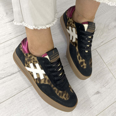 Leopard print sneakers with black and brown accents worn on a light wooden floor.