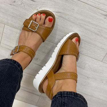 Brown sandals worn on a light wooden floor