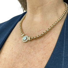 Gold necklace with a pendant worn by a person against a blue background
