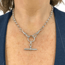 Silver necklace with a pendant on a person wearing a blue jacket.