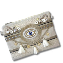 Decorative clutch bag with eye design, tassels, and embellishments on a white background
