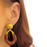 Gold and amber earring worn by a person with a plain background
