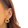 Gold earring worn by a person with a plain background