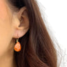 Close-up of an ear wearing a gold earring with an orange stone.