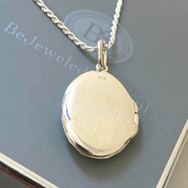 silver locket with 'mum' engraving on a chain, displayed on a branded box.