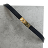 Black leather strap with a gold buckle on a gray surface