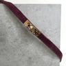 Maroon belt with gold buckle on a gray surface