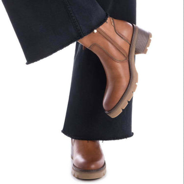 Brown leather shoes worn with black pants on a white background