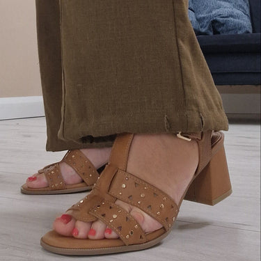 Person wearing brown pants and sandals in a room with a couch and door.