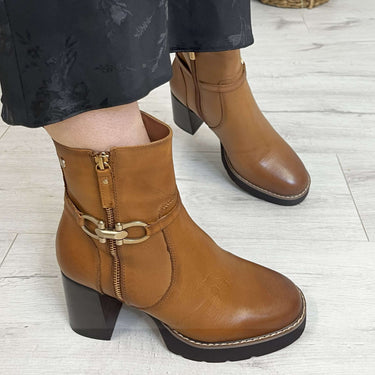 Brown leather boots worn with a dark floral dress on a light wooden floor.