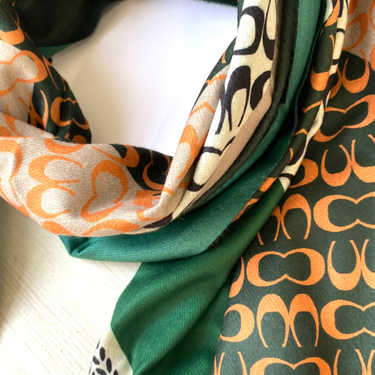 Close-up of a patterned scarf with green, orange, and black design.