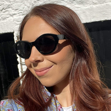 Woman wearing sunglasses with a white textured wall background