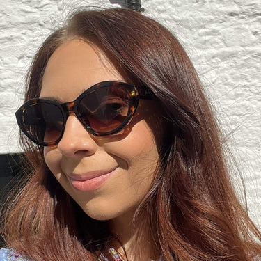 Woman wearing sunglasses with a white textured wall background