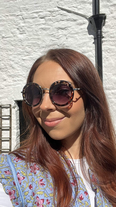 Woman wearing sunglasses with a white textured wall background