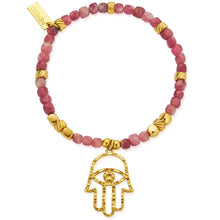 Bracelet with pink beads and gold Hamsa hand charm on a white background