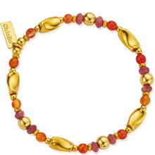 Gold bracelet with red and pink beads on a white background