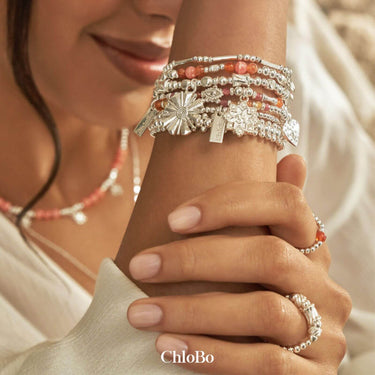 Close-up of a hand wearing multiple silver bracelets with visible 'ChloBo' branding.