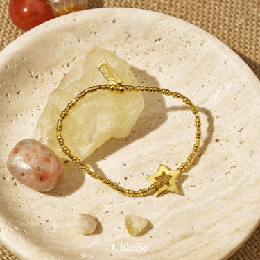 Gold bracelet with star charm on a stone surface, ChloBo brand visible