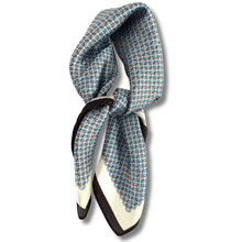 Blue patterned scarf tied around a black and white shoe on a white background