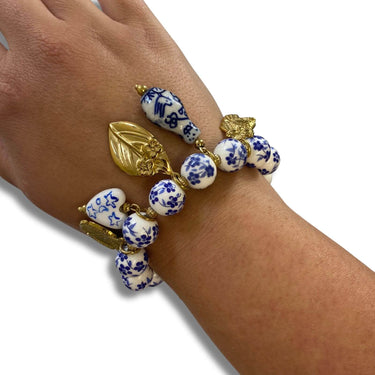 Bracelet with blue and white ceramic beads and gold accents on a wrist against a white background