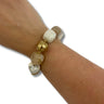 Beaded bracelet with gold and beige beads on a wrist against a white background