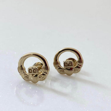 Gold earrings on a light gray background