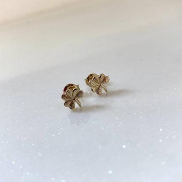 Gold four-leaf clover earrings on a white background