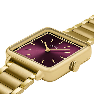 Gold watch with a purple face on a white background