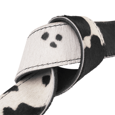 Close-up of a black and white cowhide belt with visible stitching on a white background