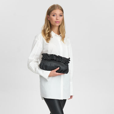 Woman holding a black clutch against a plain background