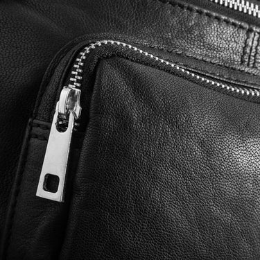 Close-up of a black leather bag with a silver zipper