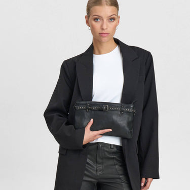 Person wearing a black blazer holding a black clutch bag on a white background