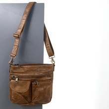 Brown leather shoulder bag on a gray background