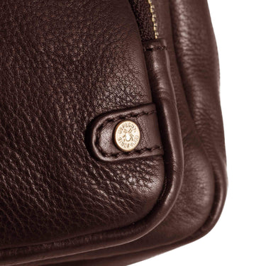 Close-up of a brown leather bag with a gold emblem on a white background