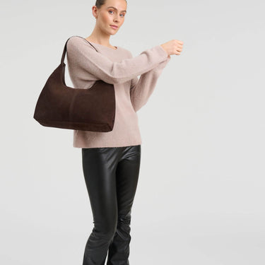 Woman holding a brown bag against a light gray background