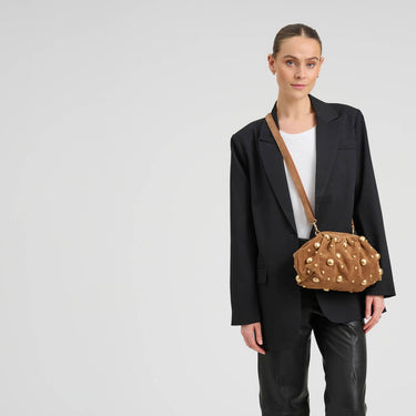 Person wearing a black suit with a brown handbag on a light gray background