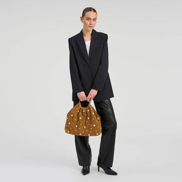 Woman holding a brown patterned handbag against a white background