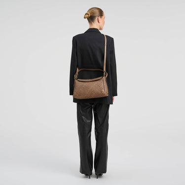 Person wearing a black outfit with a brown woven handbag on a white background