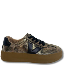 A low-top platform sneaker featuring a metallic gold and black textured upper, black laces, a black heel tab, and a thick brown platform sole.