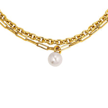 A gold-toned layered necklace featuring a textured chain, a paperclip chain, and a single dangling white pearl, shown against a plain white background.