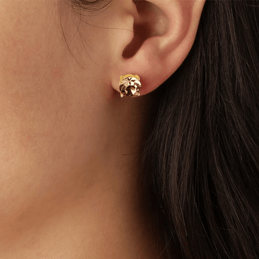 Gold earring worn by a person with dark hair